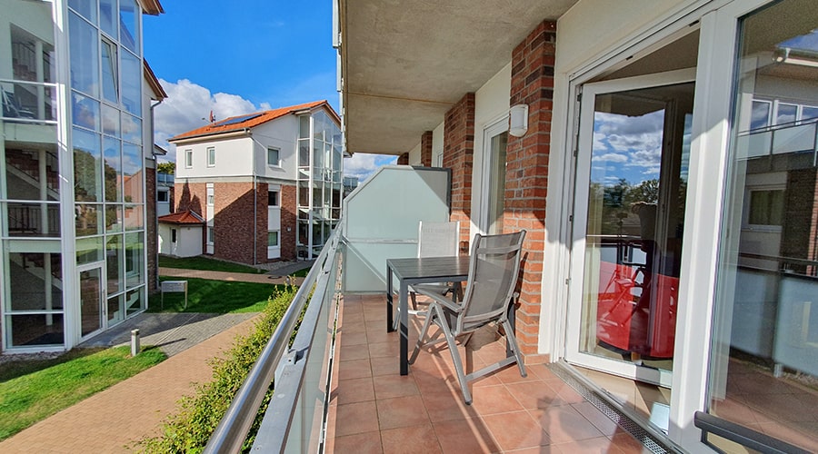 Balkon mit Tisch, Stühlen und Blick auf Ferienwohnungen